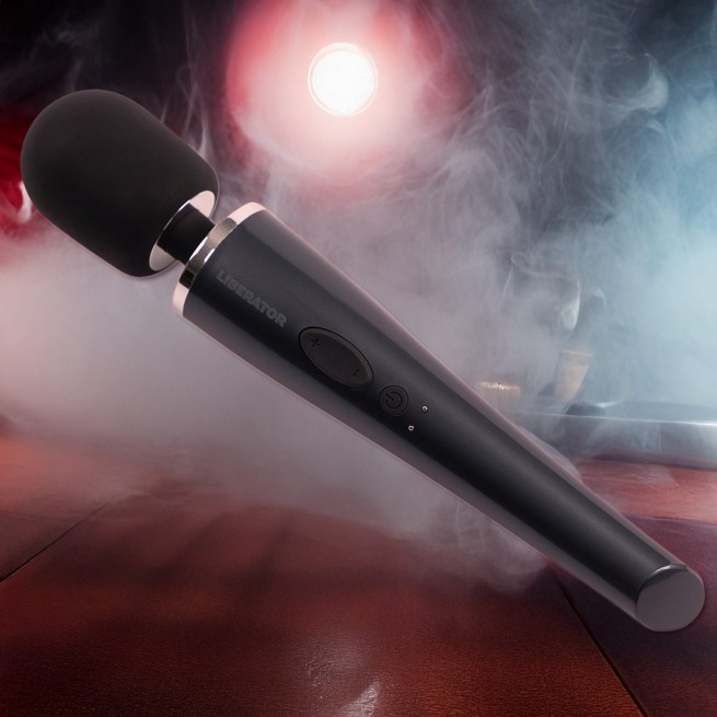 Close-up of the black wand vibrator included with the Tula Toy Mount by Liberator. Sleek design shown against moody red and smoke background.