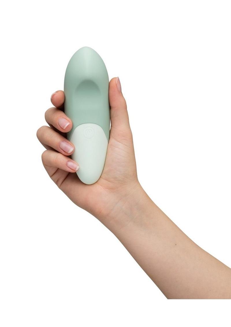 Hand holding a light green and white handheld device against a white background